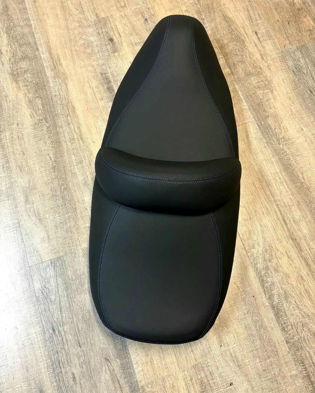 Reupholstered jet ski seat in black marine vinyl with blue contrast stitching