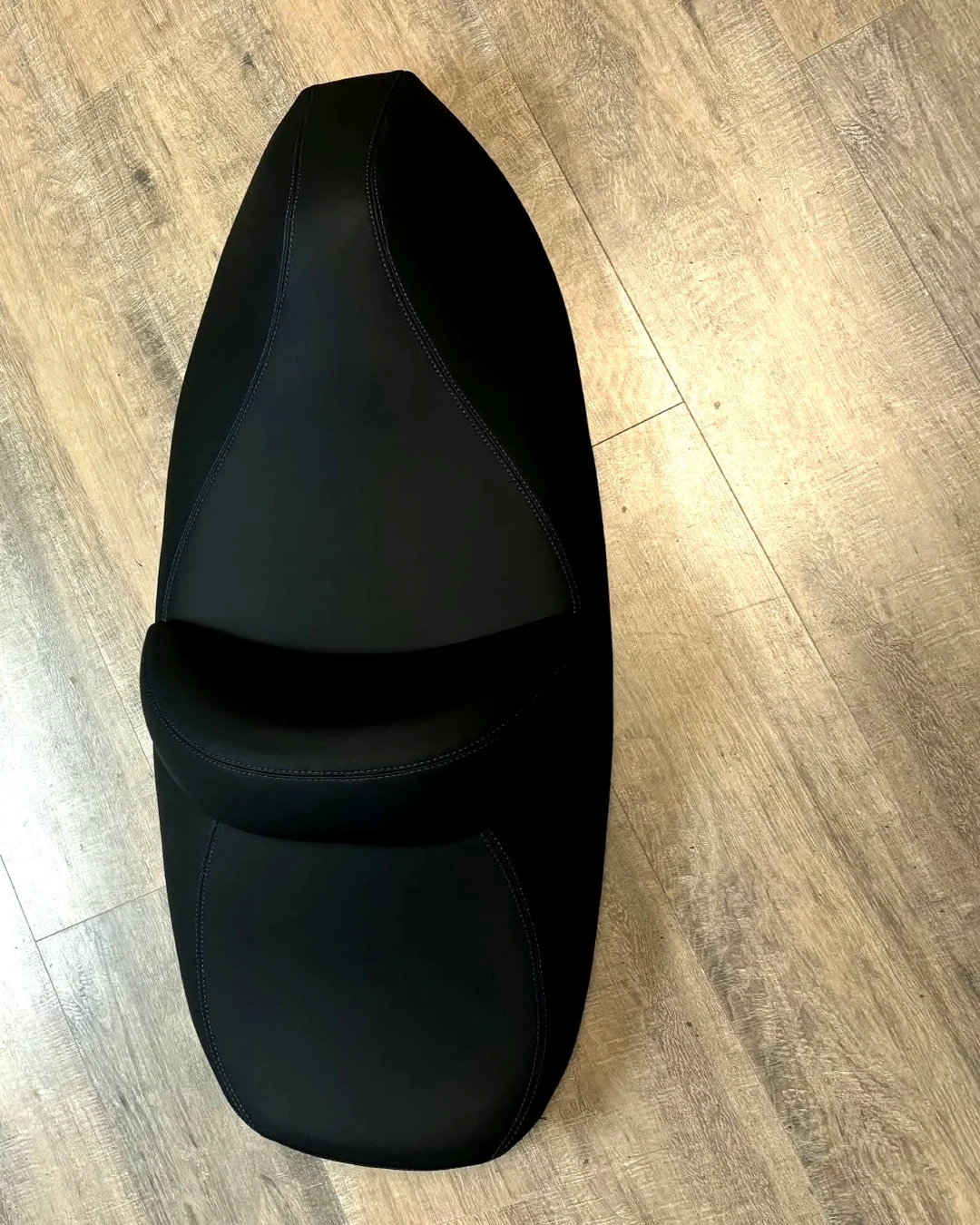 Reupholstered jet ski seat in black marine vinyl with blue contrast stitching